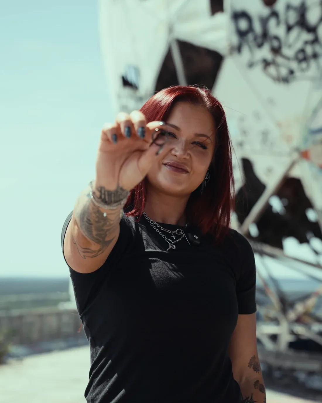 Sophia Thiel hält den MYnextRING SKY in die Kamera, im Rücken die Graffiti-Kuppel am Teufelsberg